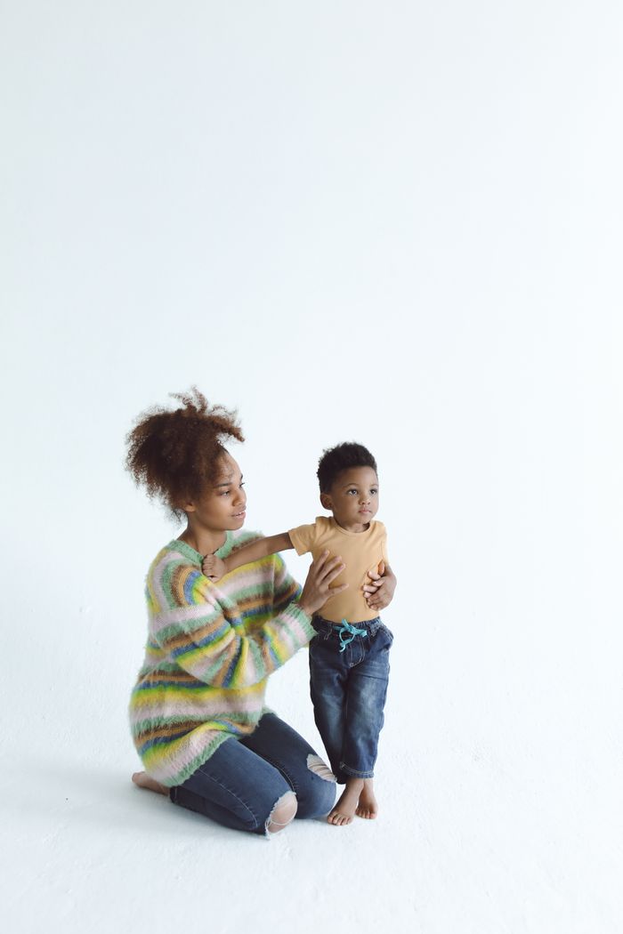 A mother teaches her child to stand, showcasing warmth and togetherness.