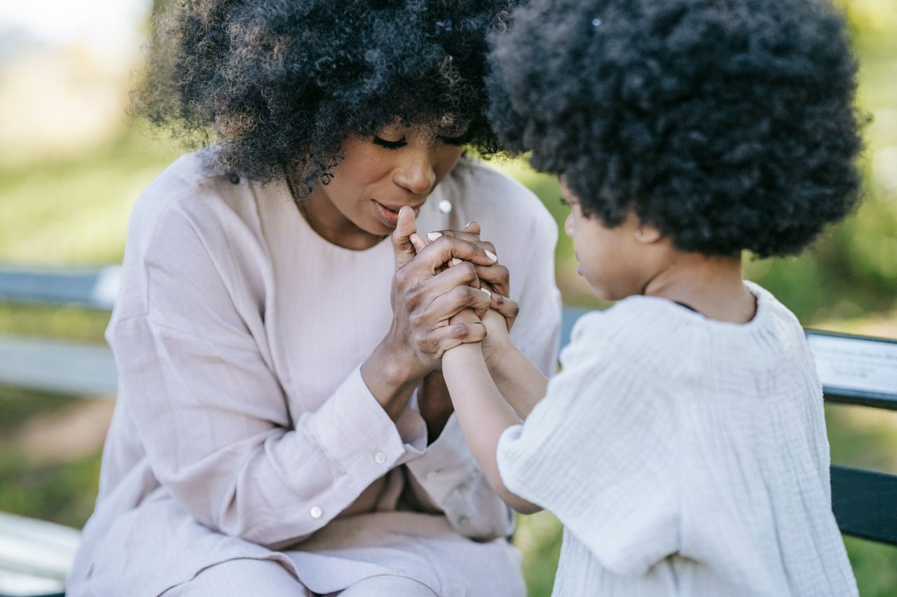A heartwarming moment between a mother and daughter holding hands outdoors.